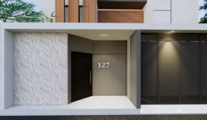 Area akses pintu utama rumah Mr. AM di sisi timur dengan pintu hitam elegan dan nomor rumah 127 pada dinding abu-abu minimalis.