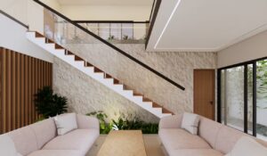 Ruang tamu rumah Mr. AM dengan dua sofa minimalis berwarna lembut, pencahayaan alami, dan view langsung ke taman samping.