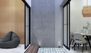 Open space kecil dengan grass block, dinding beton, dan kursi bean bag di tepinya.